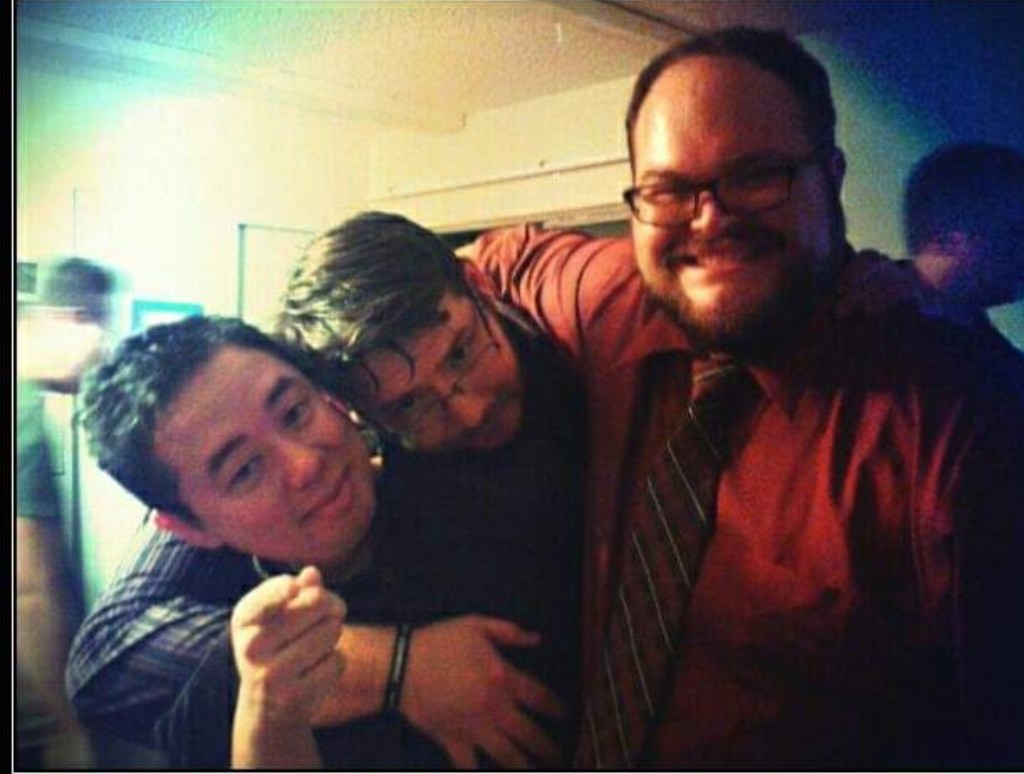 A photo of Nate and Justin holding up a squinting, very drunk Bobby, all smiling to camera.