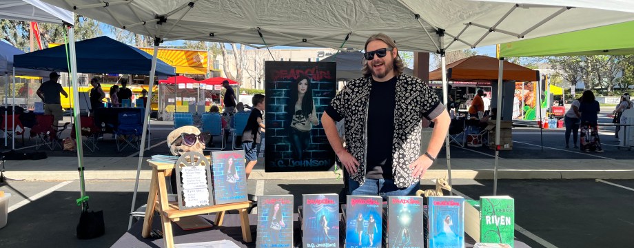 BC standing at his book fair booth, his hair has become very long